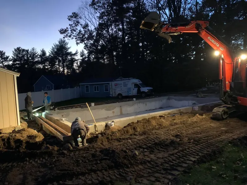 Excavator digging a pool site at dusk