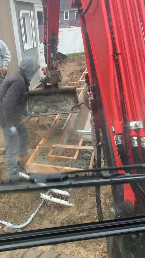 Red excavator at work beside a home