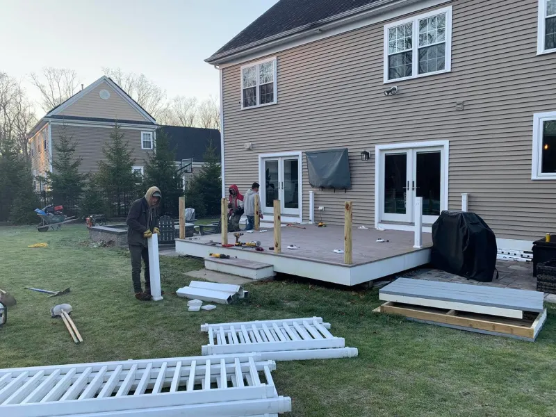 White vinyl fence sections staged beside a new deck