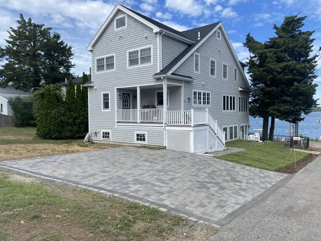 Newly installed paver patio beside a gray two-story home